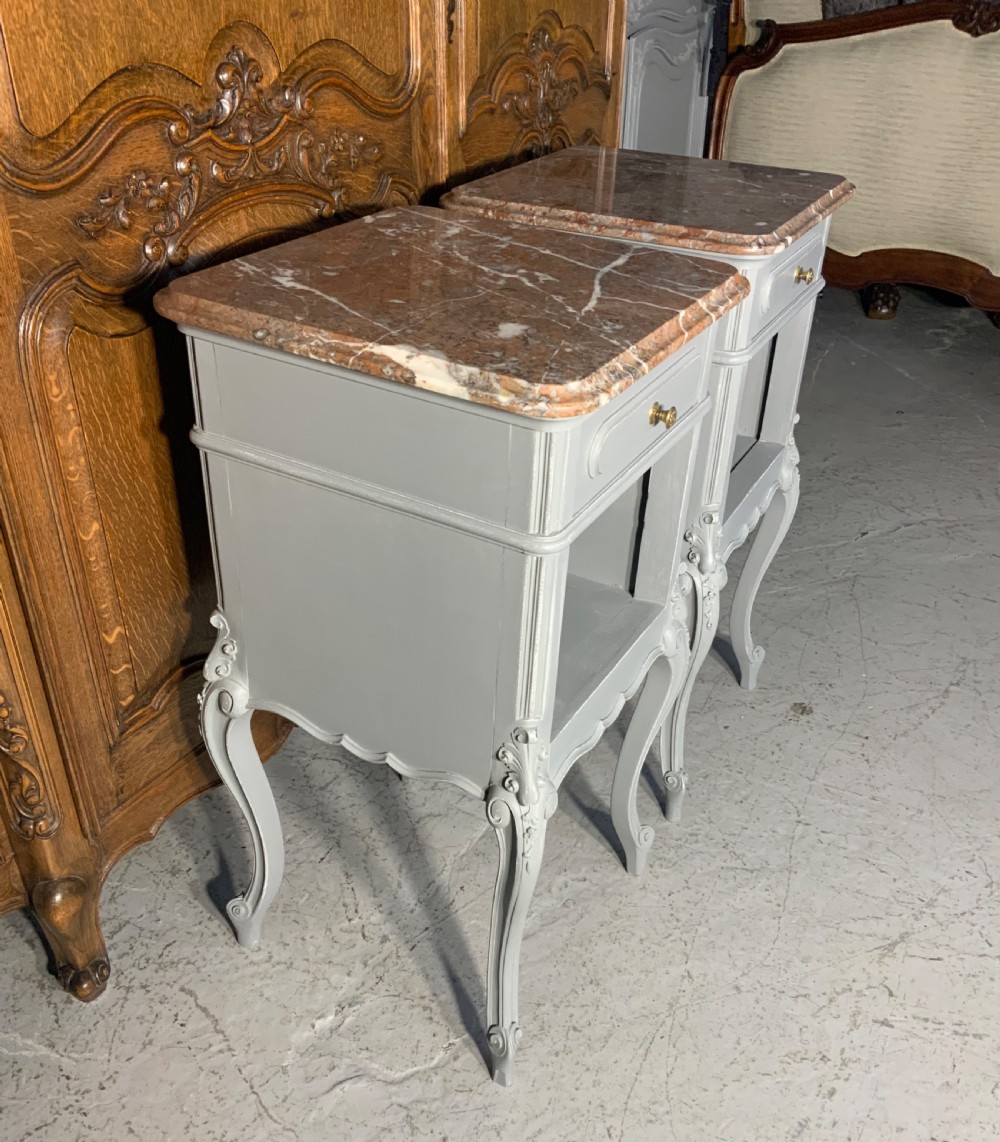 A pair of French style grey painted bedside cabinets featuring reddish-brown marble tops, single drawers with brass handles, open lower shelves, and slender cabriole legs. View V
