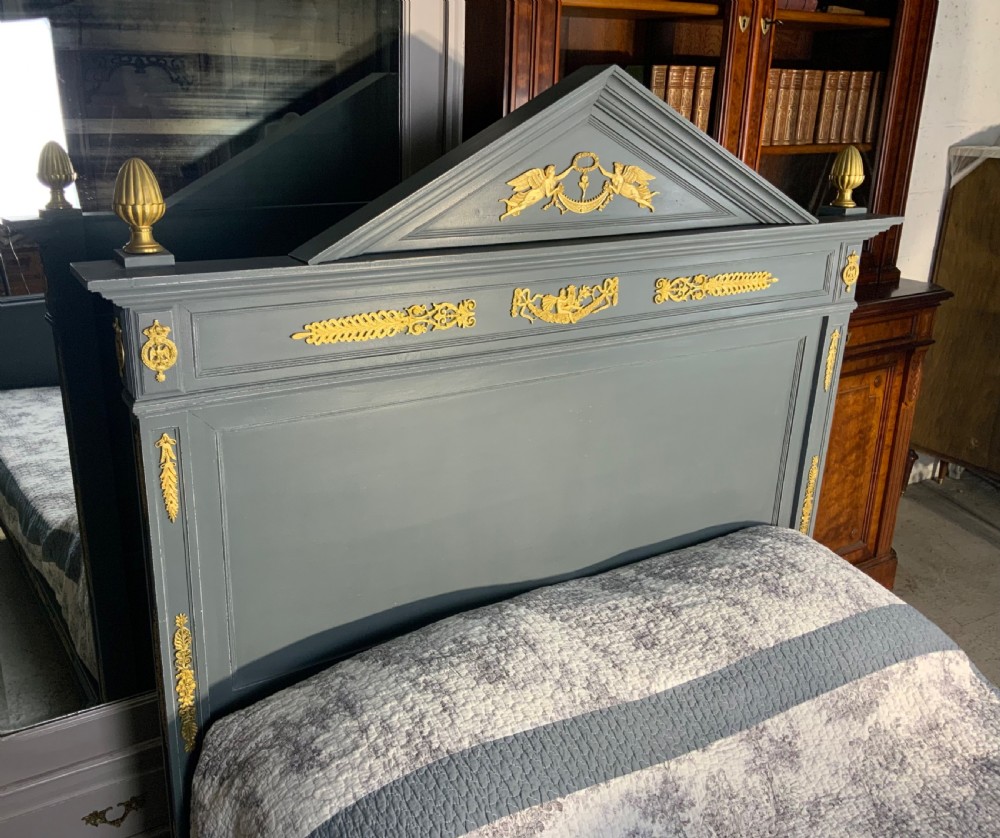 A grey painted French double bed frame decorated with gold brass mounts, featuring a central laurel wreath motif and a pediment headboard. View IX