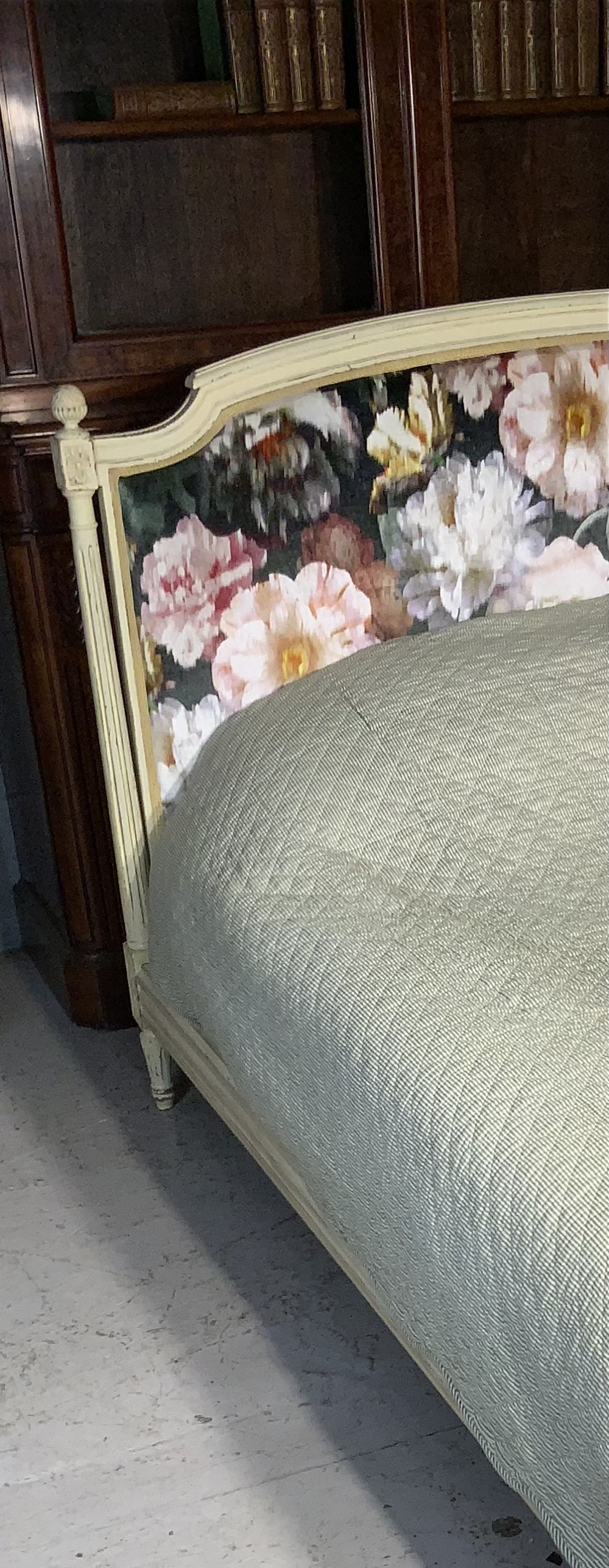 A French Louis XVI style painted bed frame with carved timber moulding and floral upholstered panels on the headboard and footboard. View VI