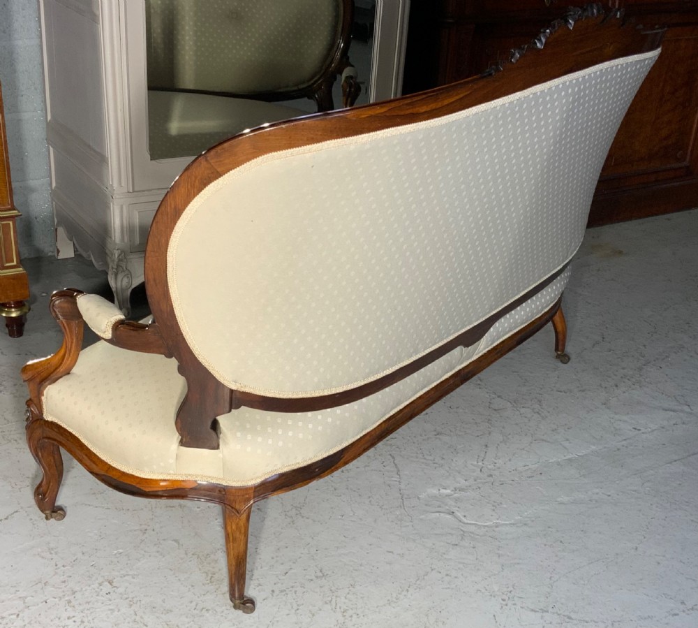 A French Rococo Revival rosewood canape featuring cream button-backed upholstery, carved cabriole legs, and a floral-carved top rail. View VIII