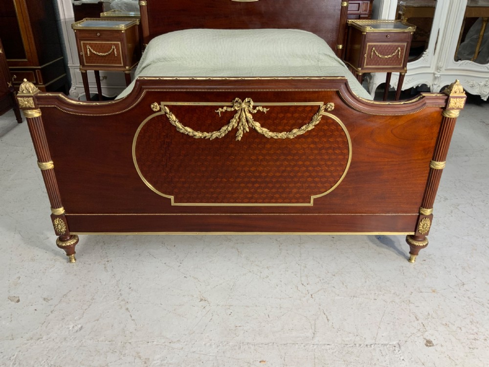 French Neoclassical mahogany bed frame featuring an oval marquetry panel, polished brass mounts, fluted columns, and two matching marble-topped bedside cabinets. View III