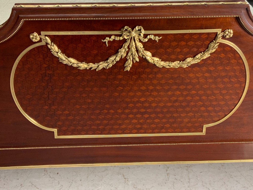 French Neoclassical mahogany bed frame featuring an oval marquetry panel, polished brass mounts, fluted columns, and two matching marble-topped bedside cabinets. View VII