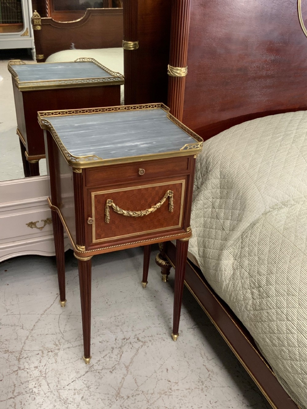 French Neoclassical mahogany bed frame featuring an oval marquetry panel, polished brass mounts, fluted columns, and two matching marble-topped bedside cabinets. View XI