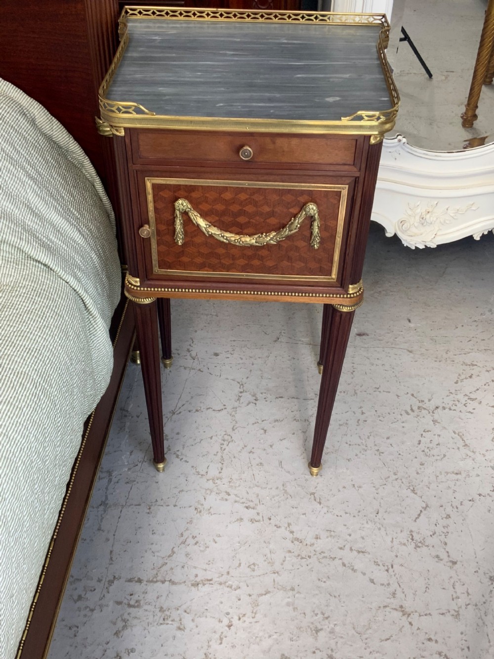 French Neoclassical mahogany bed frame featuring an oval marquetry panel, polished brass mounts, fluted columns, and two matching marble-topped bedside cabinets. View XIV