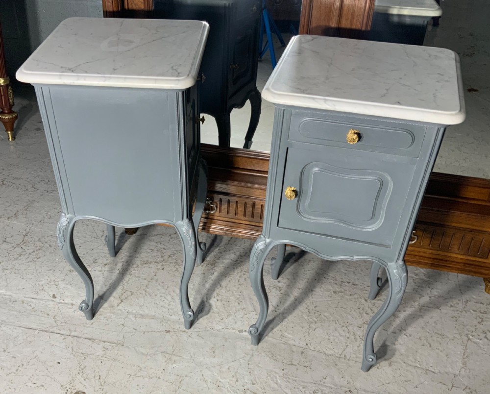 A pair of dark grey painted French bedside cabinets featuring white marble tops, single drawers, cupboard doors, carved accents, and cabriole legs. View V