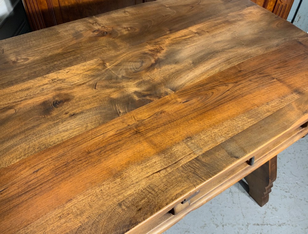 A solid walnut writing desk featuring two carved front drawers with iron drop handles, supported by splayed trestle legs and a curved wrought iron stretcher. View VI