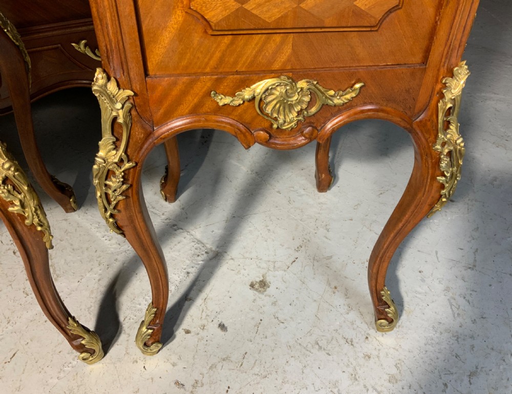 A French Louis XV style king-size bedstead featuring geometric parquetry inlay, carved central motif, and gilt-bronze mounts, flanked by two matching bedside cabinets with marble tops. View XII