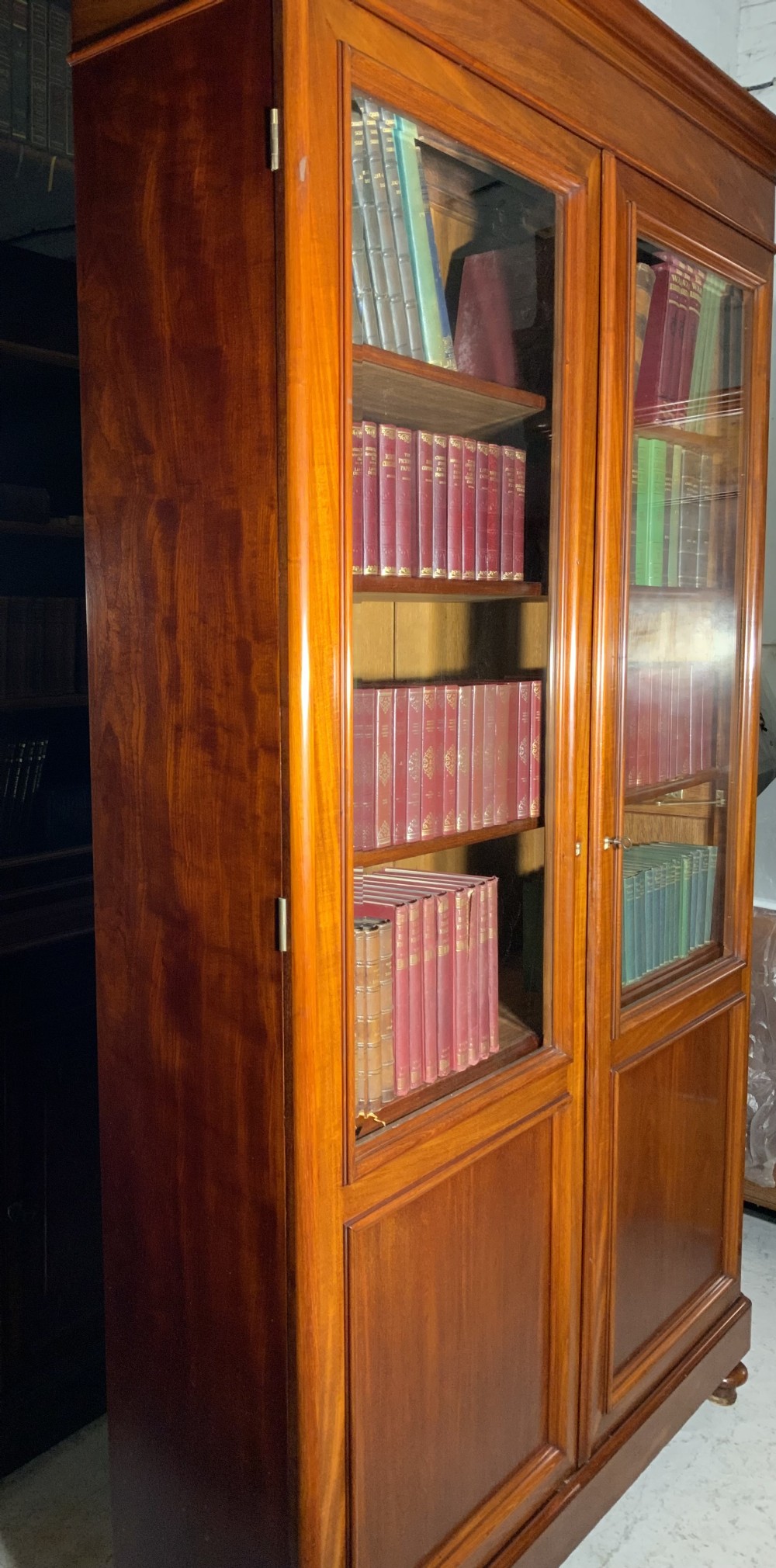 A tall French mahogany bookcase featuring two full-length glazed and panelled doors with turned feet. View VII