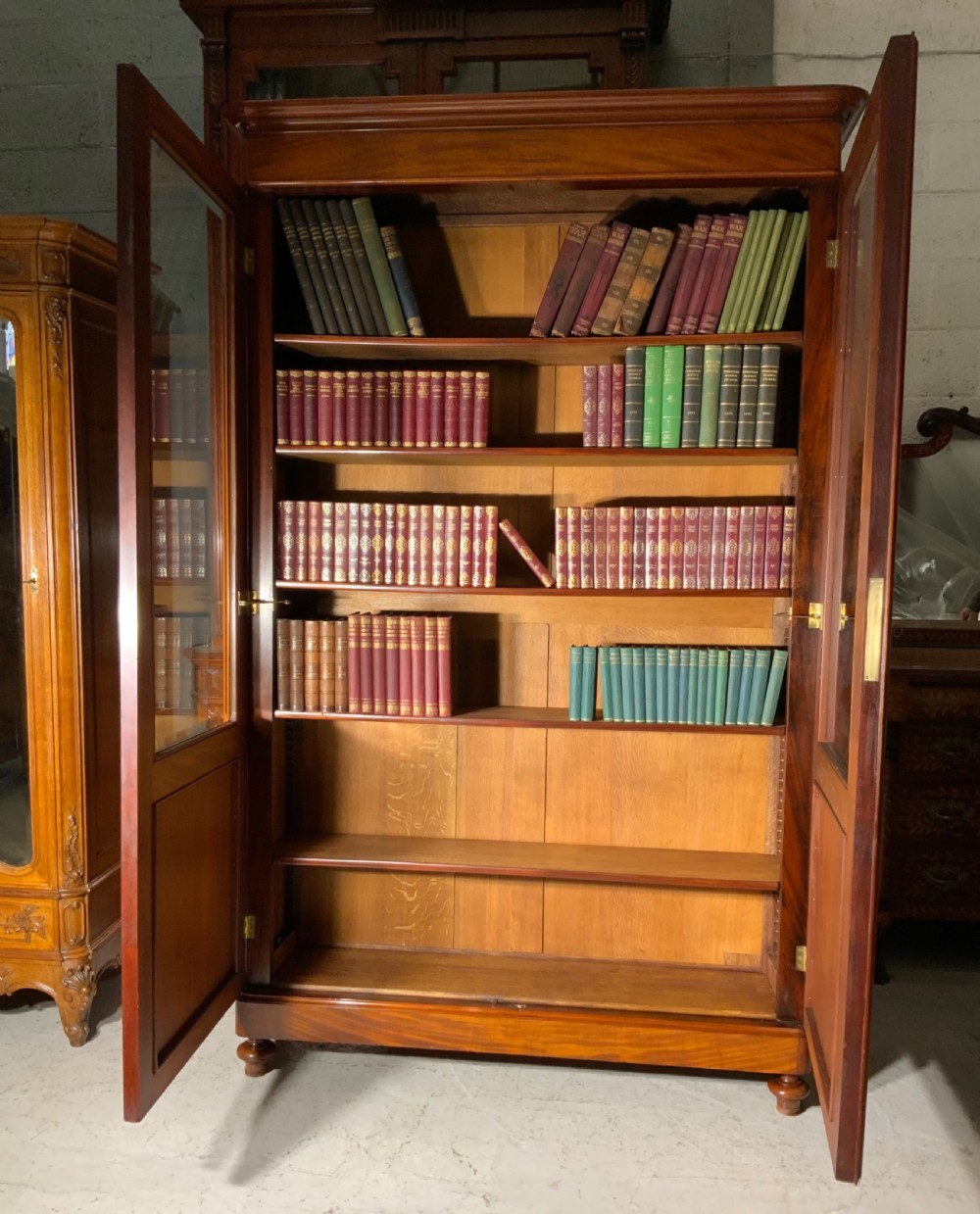 A tall French mahogany bookcase featuring two full-length glazed and panelled doors with turned feet. View X