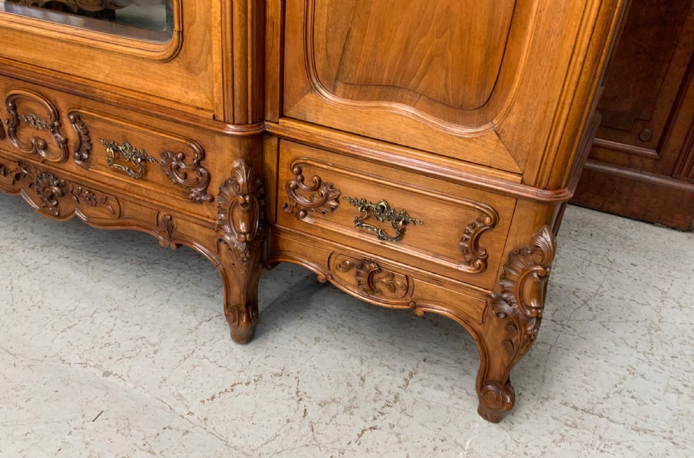 A large French carved walnut armoire featuring three mirrored doors, Rococo cresting pediment, and cabriole feet. View V