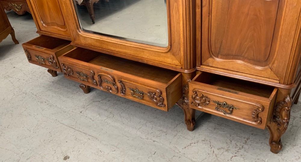 A large French carved walnut armoire featuring three mirrored doors, Rococo cresting pediment, and cabriole feet. View VI