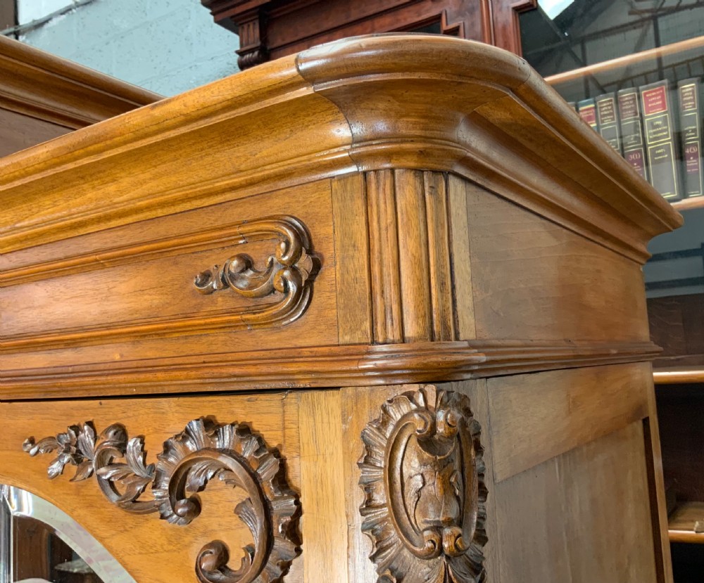 A large French carved walnut armoire featuring three mirrored doors, Rococo cresting pediment, and cabriole feet. View VII