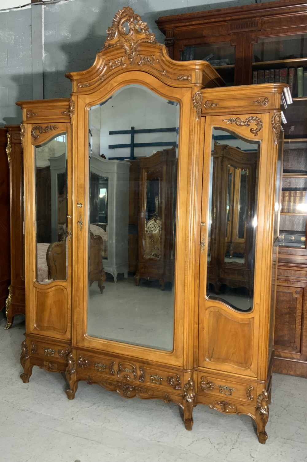 A large French carved walnut armoire featuring three mirrored doors, Rococo cresting pediment, and cabriole feet. View X