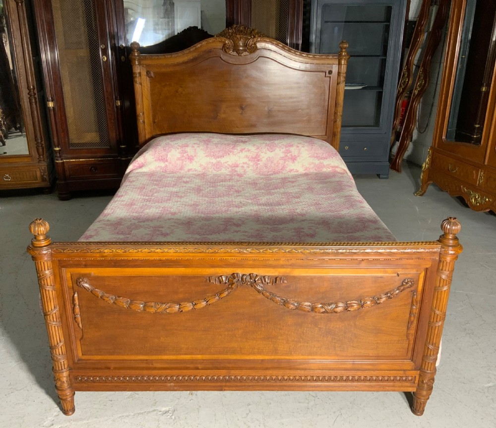 Carved mahogany king-size bedstead featuring fluted corner posts, an arched crest headboard, and carved leaf swags on the footboard. View II