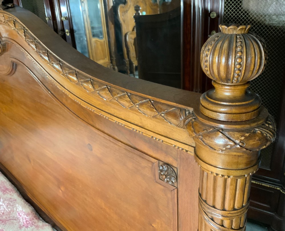 Carved mahogany king-size bedstead featuring fluted corner posts, an arched crest headboard, and carved leaf swags on the footboard. View VIII
