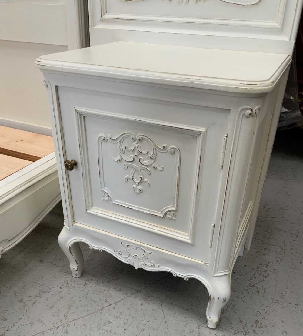 A cream painted French Rococo style bedstead featuring detailed foliage carving, serpentine headboard, matching footboard, and two bedside cabinets. View XI