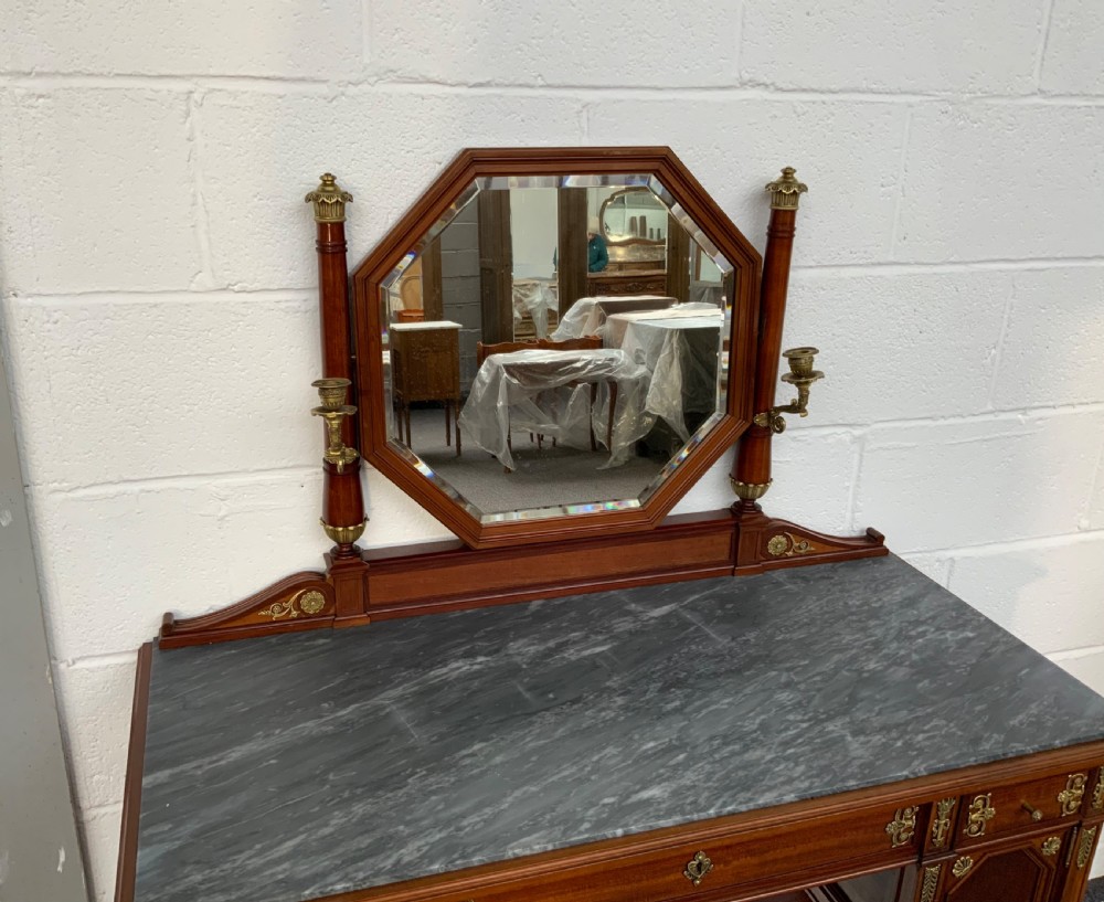 A French mahogany dressing table featuring a grey marble surface, an octagonal mirror flanked by twin brass candle holders, and intricate brass mounts. View V
