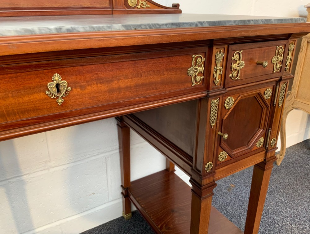 A French mahogany dressing table featuring a grey marble surface, an octagonal mirror flanked by twin brass candle holders, and intricate brass mounts. View IX