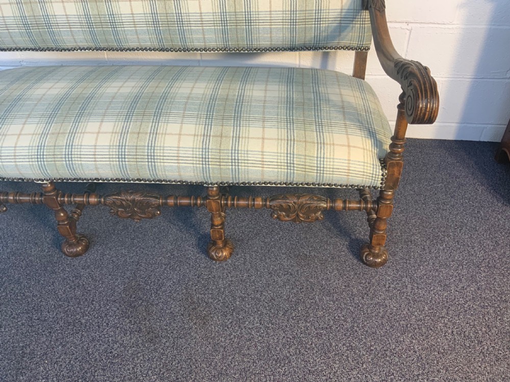 An upholstered French carved walnut settee featuring a green and cream check fabric, carved scroll arms, turned stretchers, and brass studding. View II