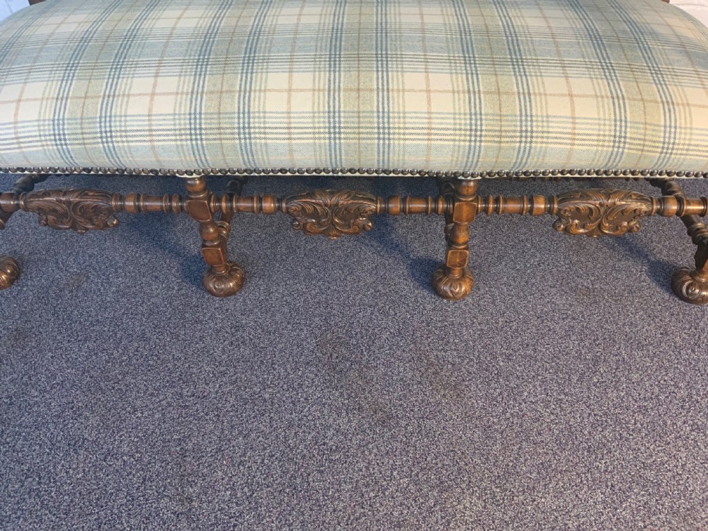 An upholstered French carved walnut settee featuring a green and cream check fabric, carved scroll arms, turned stretchers, and brass studding. View III