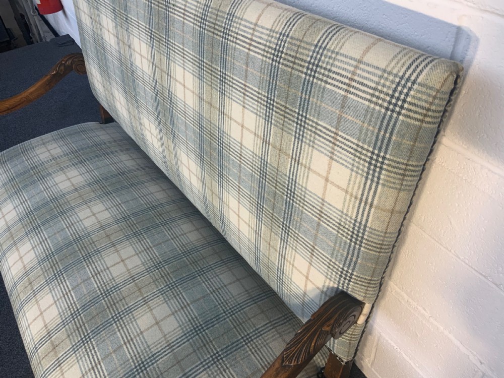 An upholstered French carved walnut settee featuring a green and cream check fabric, carved scroll arms, turned stretchers, and brass studding. View VIII