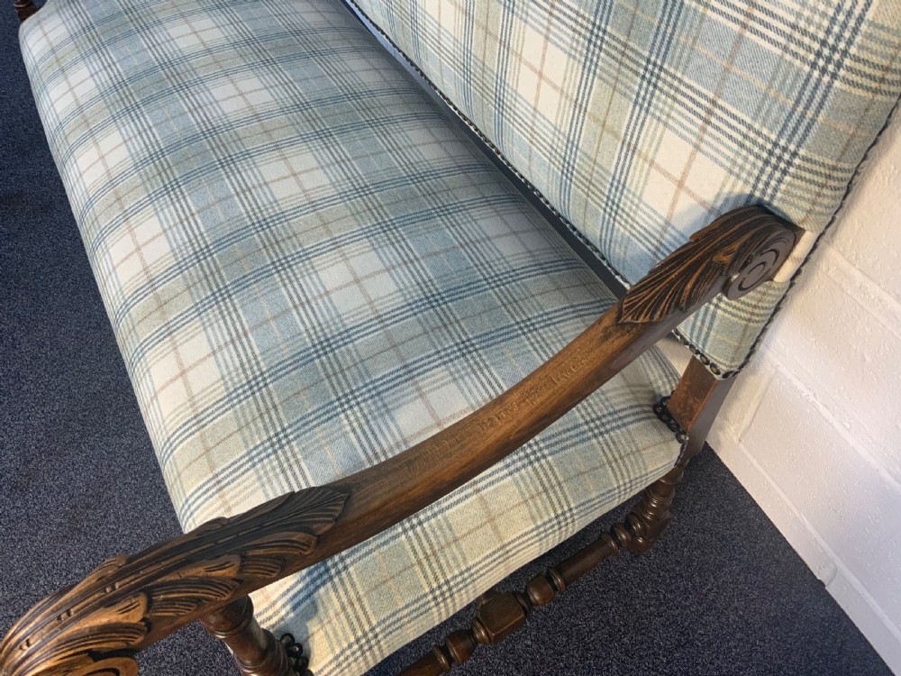An upholstered French carved walnut settee featuring a green and cream check fabric, carved scroll arms, turned stretchers, and brass studding. View IX