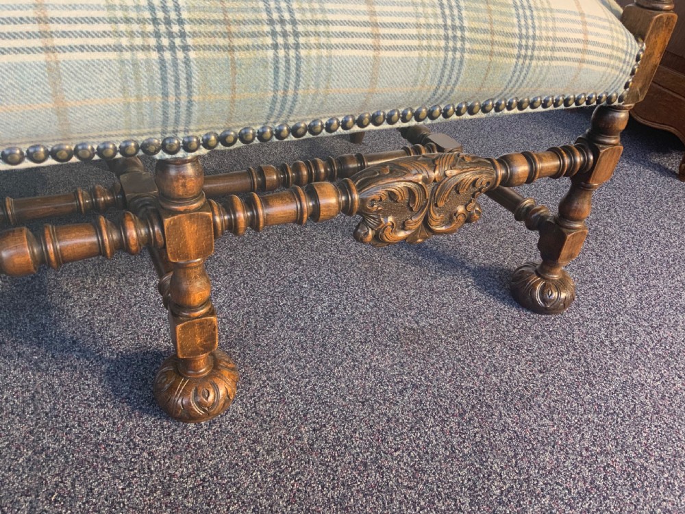 An upholstered French carved walnut settee featuring a green and cream check fabric, carved scroll arms, turned stretchers, and brass studding. View XII