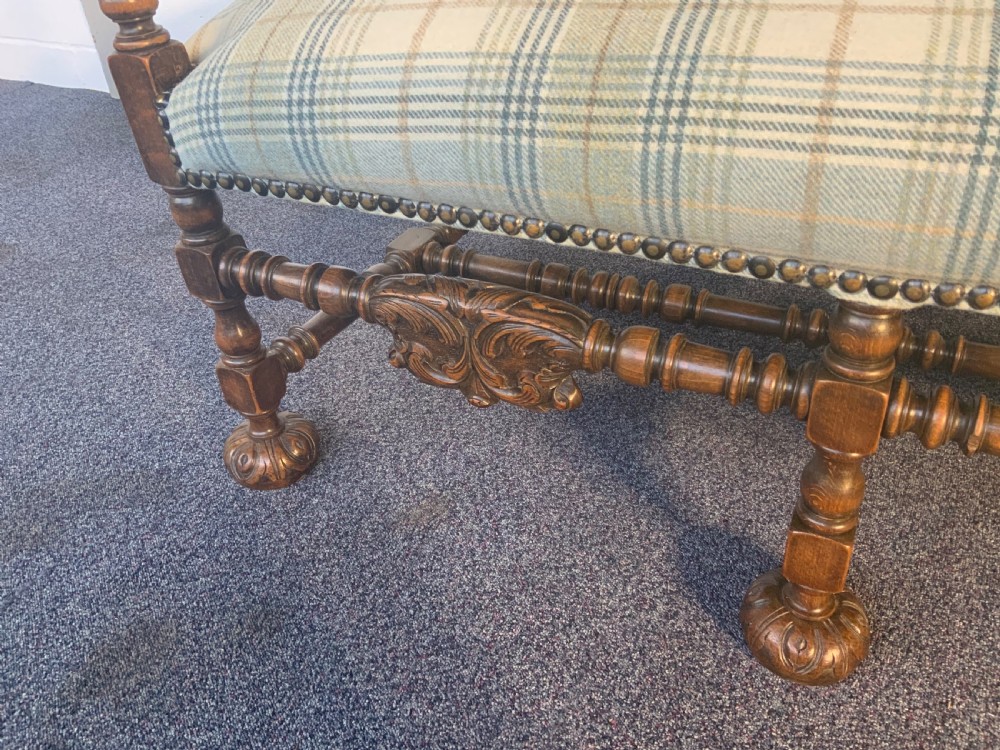 An upholstered French carved walnut settee featuring a green and cream check fabric, carved scroll arms, turned stretchers, and brass studding. View XIII