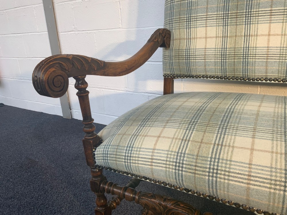 An upholstered French carved walnut settee featuring a green and cream check fabric, carved scroll arms, turned stretchers, and brass studding. View XIV