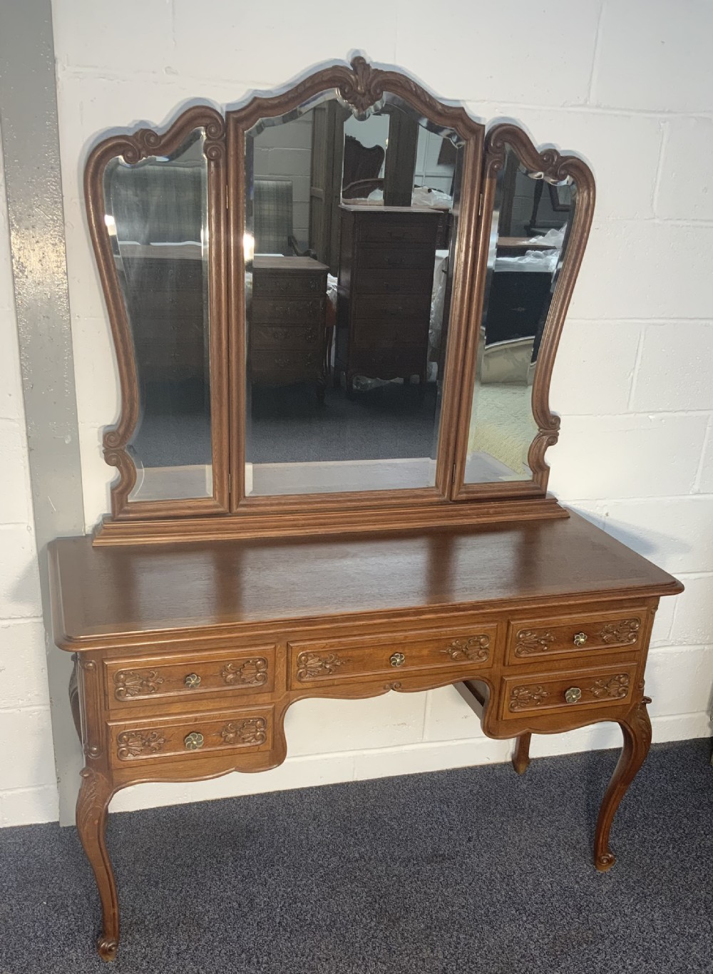 A carved oak French dressing table with a central tri-fold mirror, five carved drawers, metal handles, and curved cabriole legs. View V