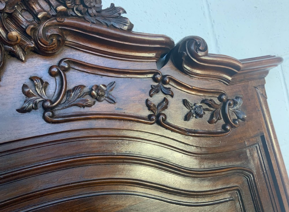A tall carved walnut trumeau mirror featuring an ornate shell crest, carved floral panel, and arched frame. View VII