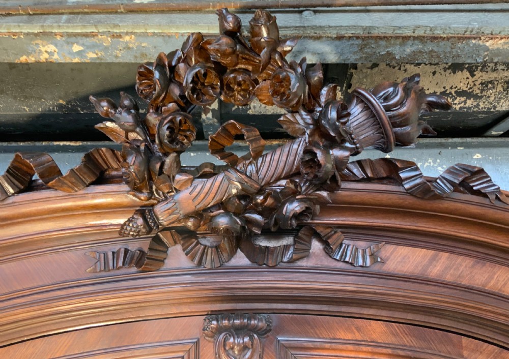 A tall 19th-century French rosewood armoire with two full-length mirrored doors, an arched pediment topped with a foliage crest carving, and fluted corner columns. View XII