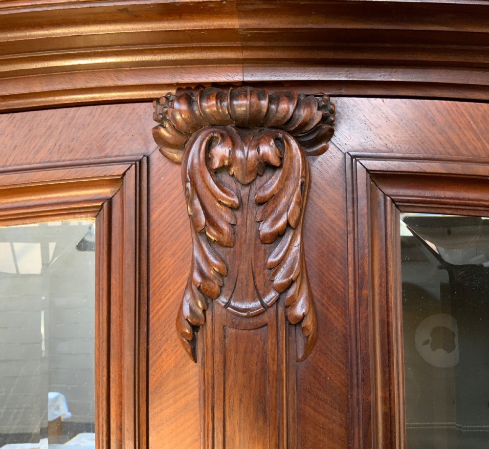 A tall 19th-century French rosewood armoire with two full-length mirrored doors, an arched pediment topped with a foliage crest carving, and fluted corner columns. View XIII