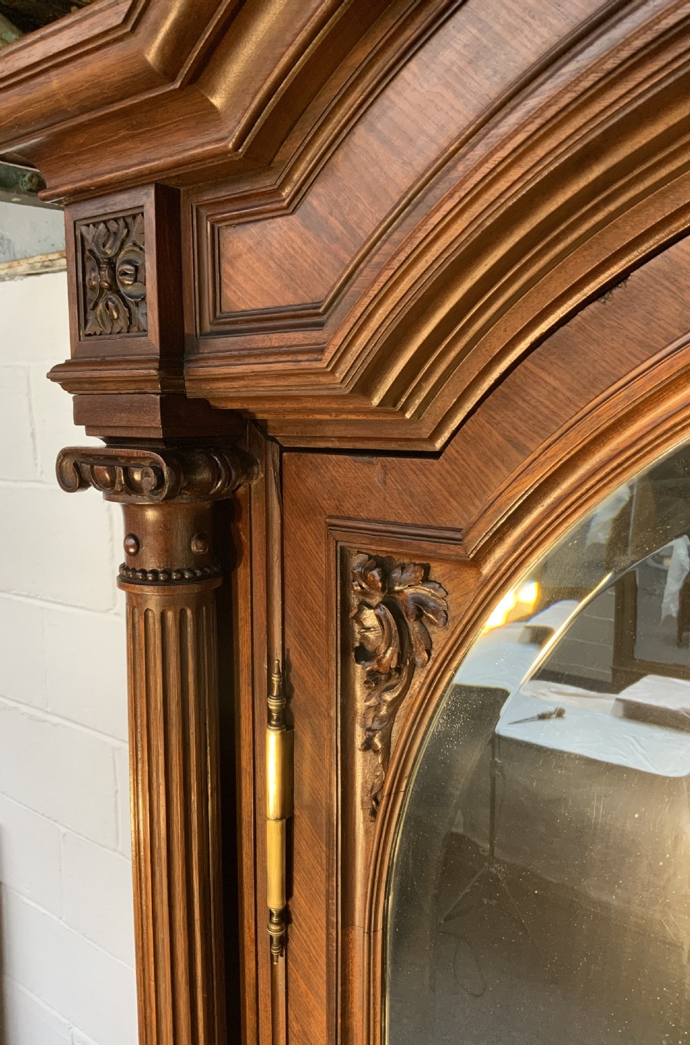 A tall 19th-century French rosewood armoire with two full-length mirrored doors, an arched pediment topped with a foliage crest carving, and fluted corner columns. View XIV