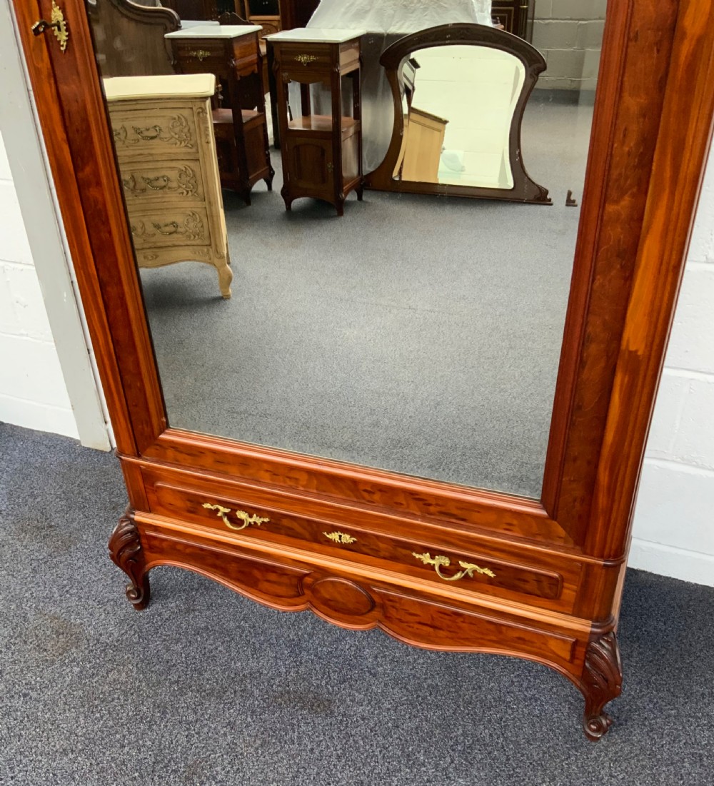 A tall single-door French mahogany armoire featuring an arched mirror door, detailed floral carved cresting, a bottom drawer, and cabriole feet. View II
