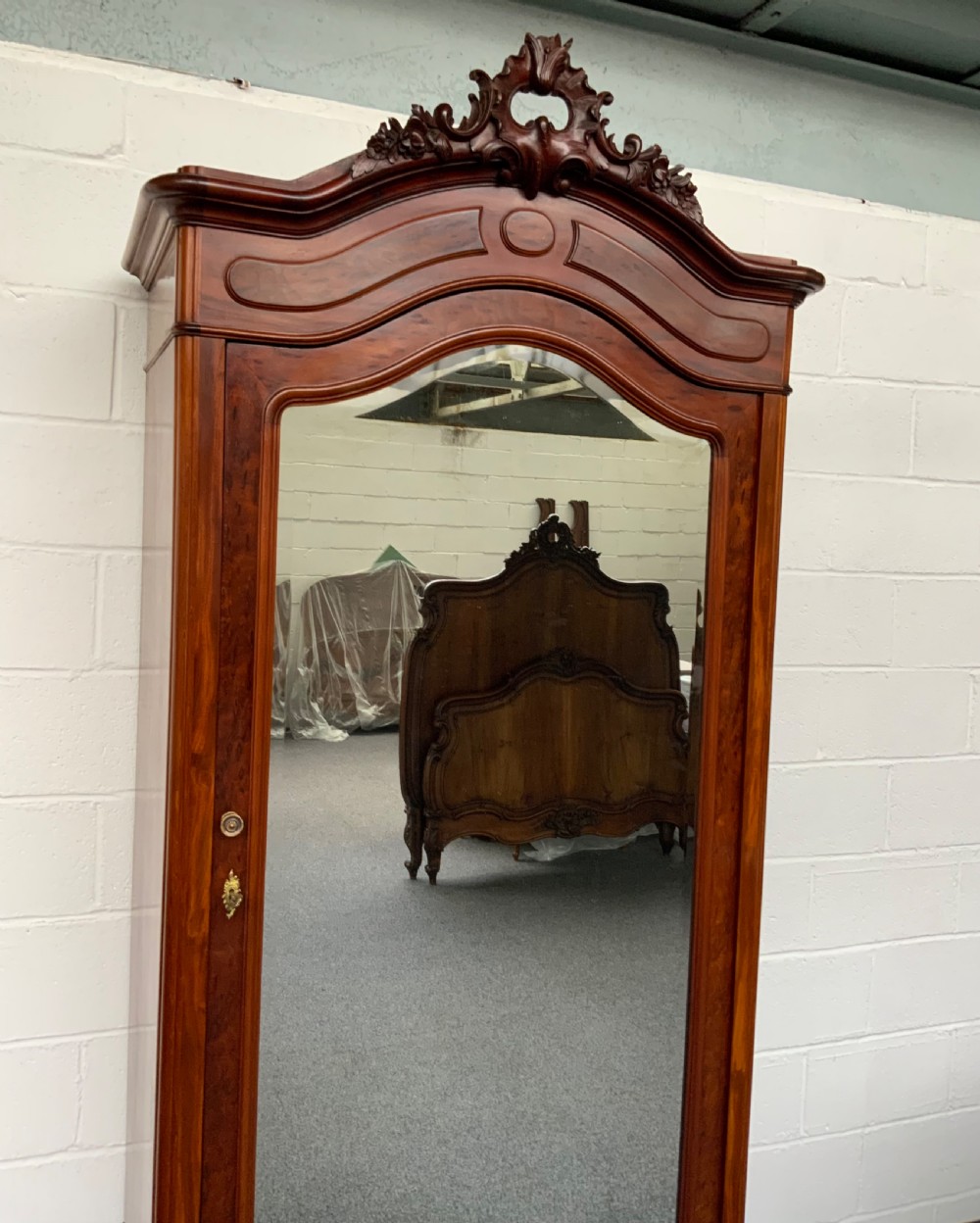 A tall single-door French mahogany armoire featuring an arched mirror door, detailed floral carved cresting, a bottom drawer, and cabriole feet. View III