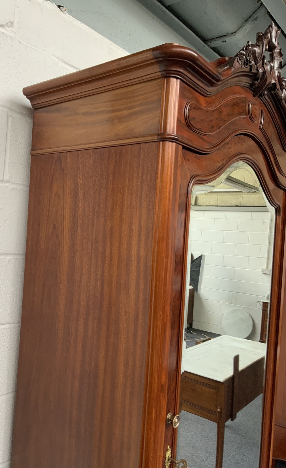 A tall single-door French mahogany armoire featuring an arched mirror door, detailed floral carved cresting, a bottom drawer, and cabriole feet. View IV