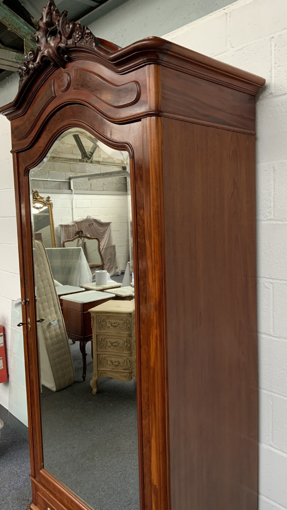 A tall single-door French mahogany armoire featuring an arched mirror door, detailed floral carved cresting, a bottom drawer, and cabriole feet. View V