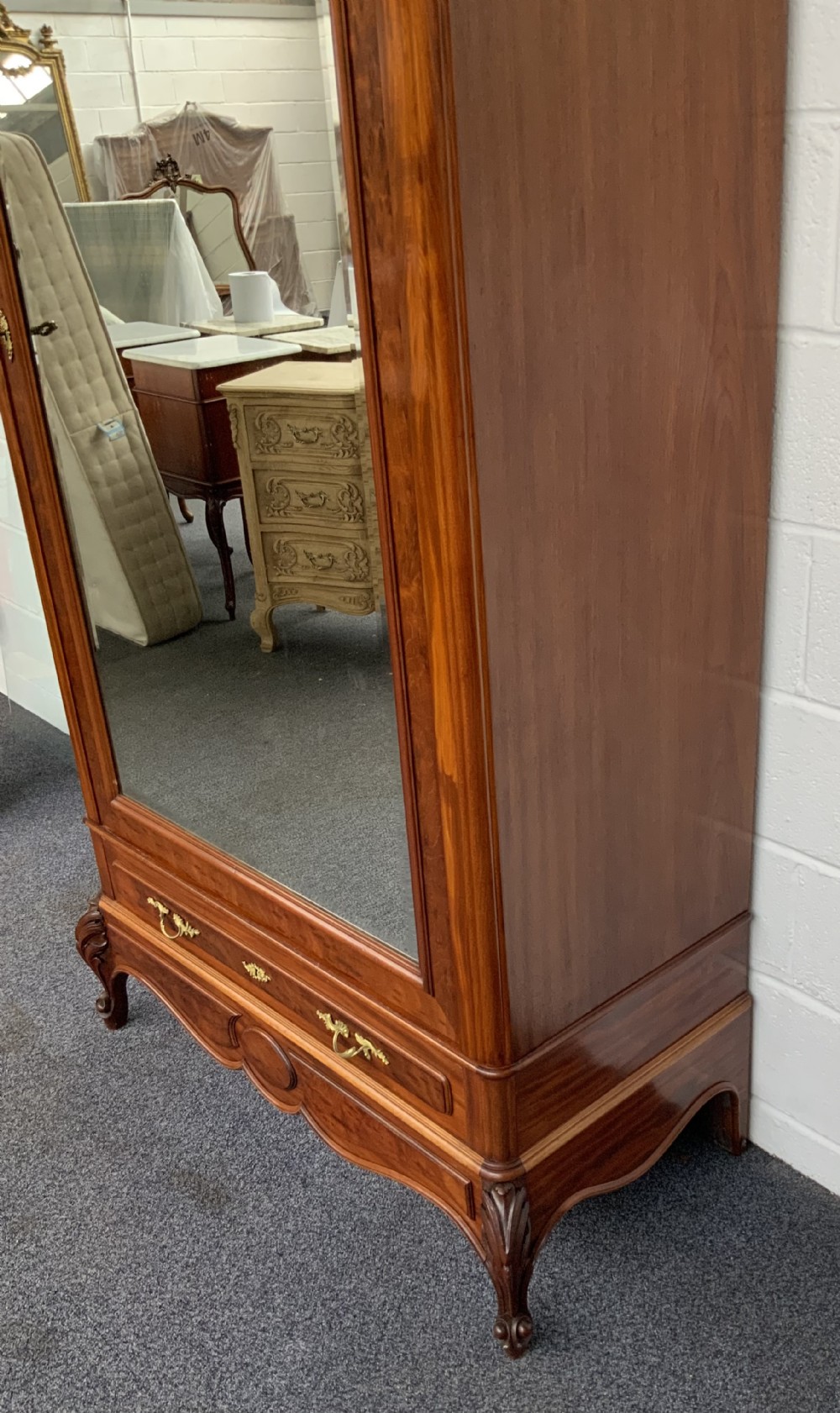 A tall single-door French mahogany armoire featuring an arched mirror door, detailed floral carved cresting, a bottom drawer, and cabriole feet. View VII