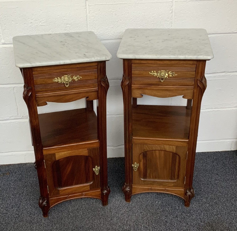 A pair of French Art Nouveau mahogany bedside cabinets featuring white marble tops, single drawers with brass handles, open middle shelves, and lower cupboards. View II