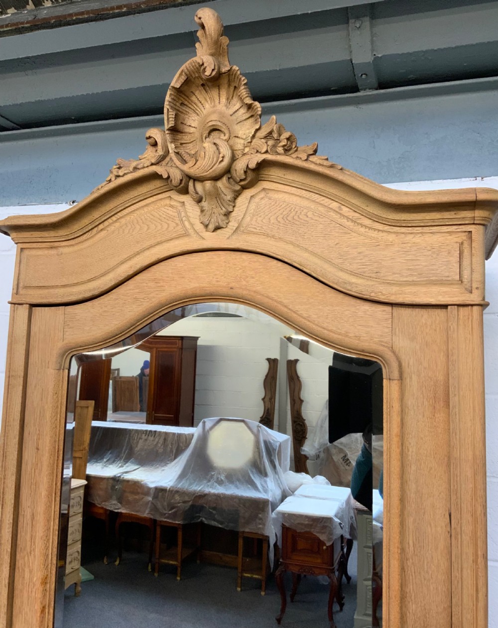 A tall bleached oak French armoire featuring a single arched mirrored door, hand-carved cresting, lower drawer, and cabriole feet. View IV