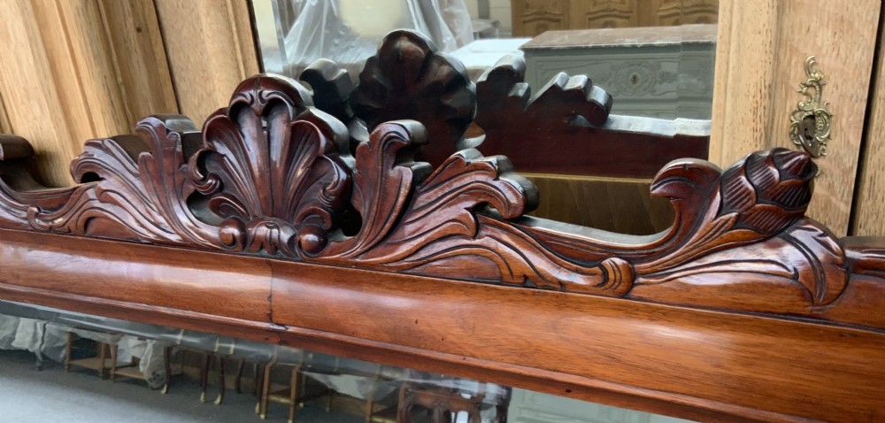 A French arched walnut mirror featuring a carved crest motif, moulded frame, and low feet. View II