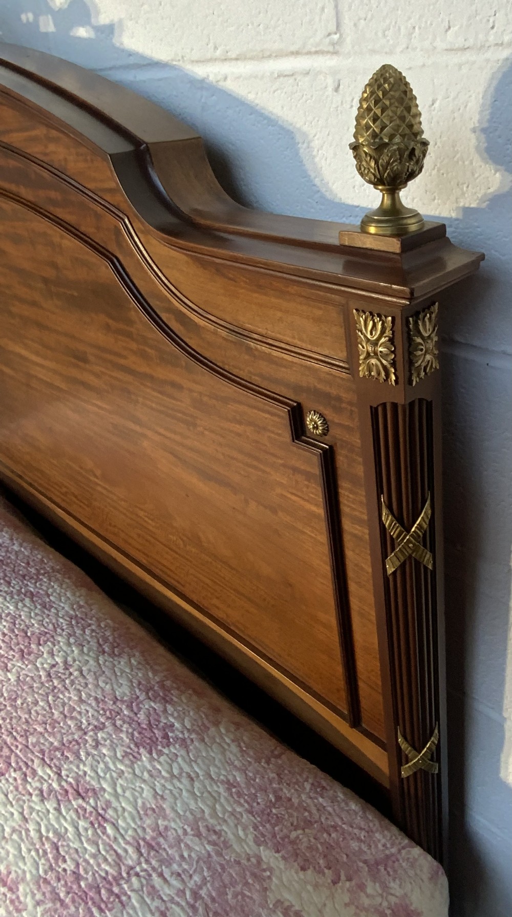A French Neoclassical king-size wooden bedstead featuring detailed brass swags, ribbon cresting, finials, and an oval medallion motif on the footboard. View X