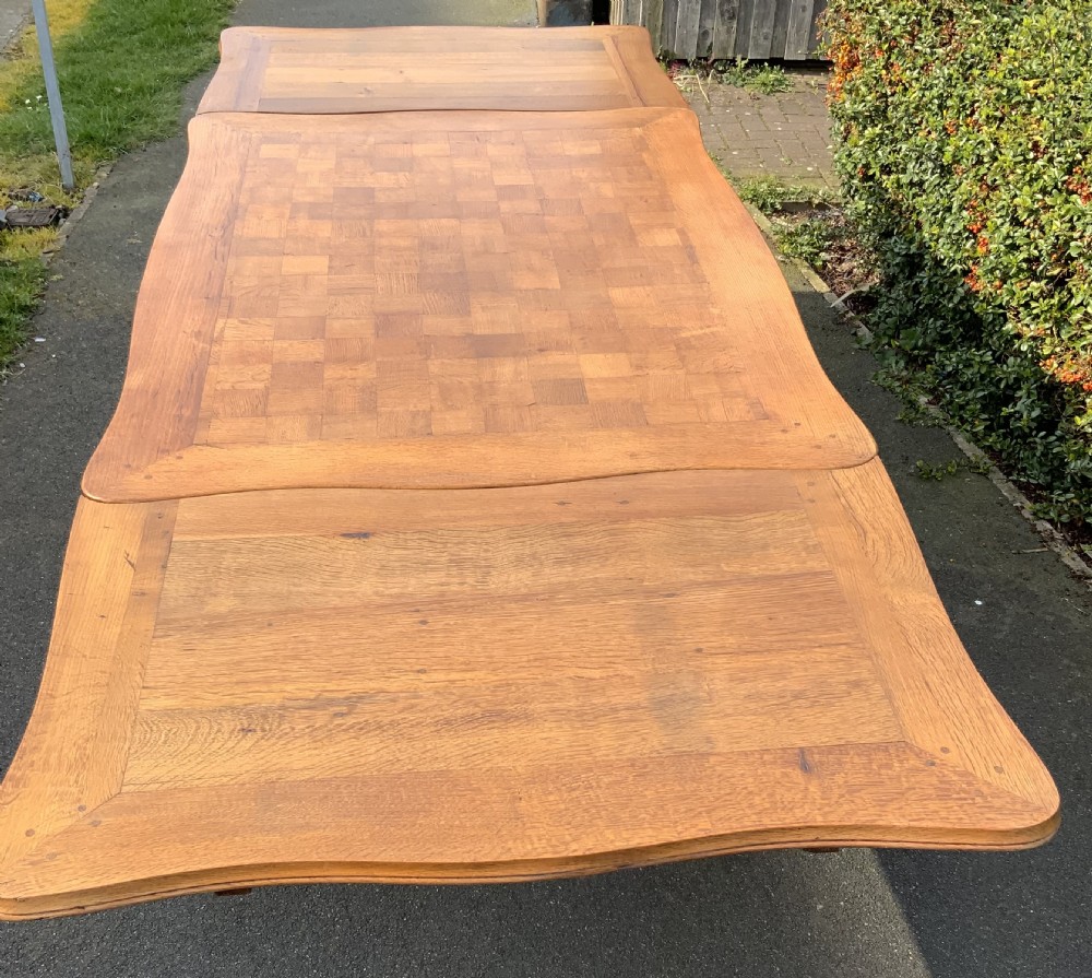 A French Provincial carved oak draw leaf dining table featuring a parquetry top, carved aprons, and cabriole legs. View VI