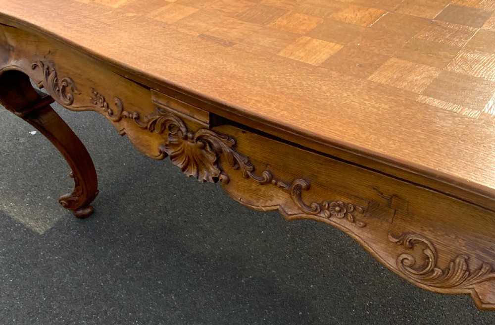A French Provincial carved oak draw leaf dining table featuring a parquetry top, carved aprons, and cabriole legs. View VIII