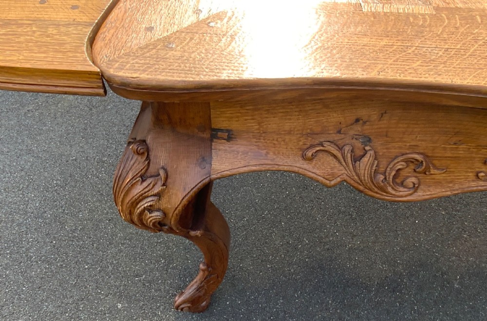 A French Provincial carved oak draw leaf dining table featuring a parquetry top, carved aprons, and cabriole legs. View IX