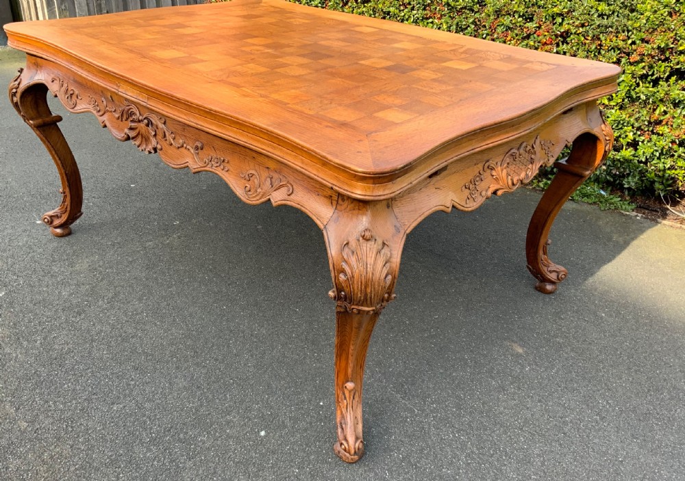 A French Provincial carved oak draw leaf dining table featuring a parquetry top, carved aprons, and cabriole legs. View XIII