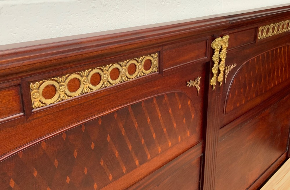 A French Empire style mahogany bed frame with diamond parquetry veneer panels and elaborate gilt brass wreath and urn mounts. View IX