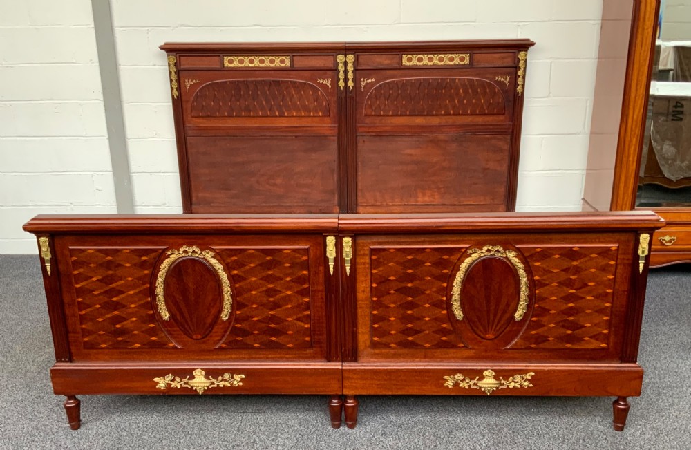 A French Empire style mahogany bed frame with diamond parquetry veneer panels and elaborate gilt brass wreath and urn mounts. View XV