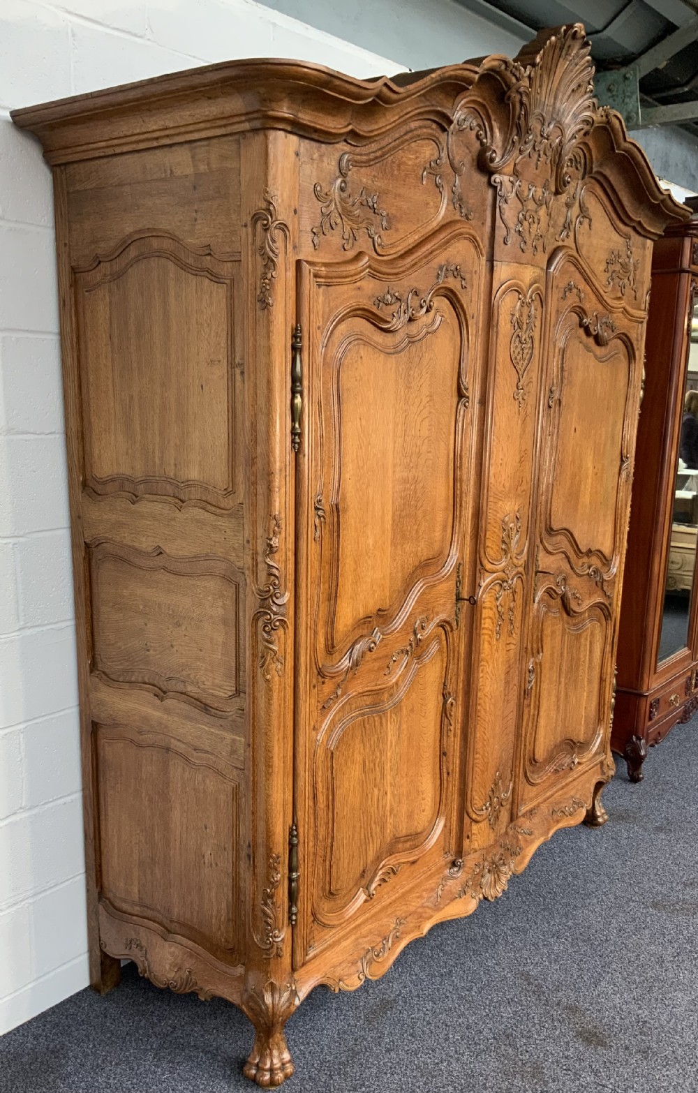 A large French Provincial carved oak armoire featuring double panelled doors, intricate cresting, brass hardware, and cabriole feet. View XII